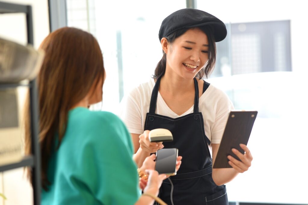 バーコードリーダーでキャッシュレス決済をする店員